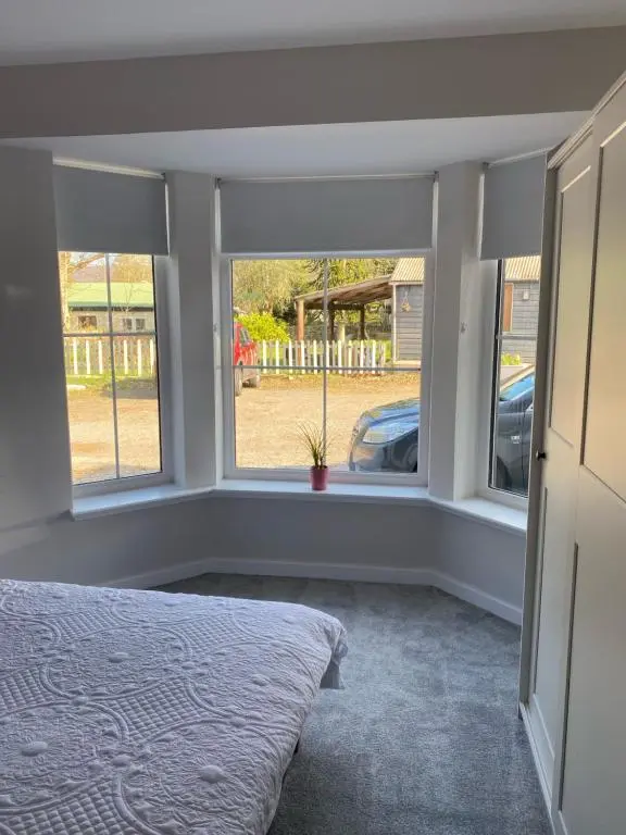a bedroom with a bed and two windows at Loch Ness House Blairbeg in Drumnadrochit