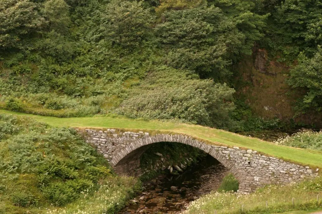 a stone bridge in the middle of a field at Craiglea Lodge & Barn in Latheron