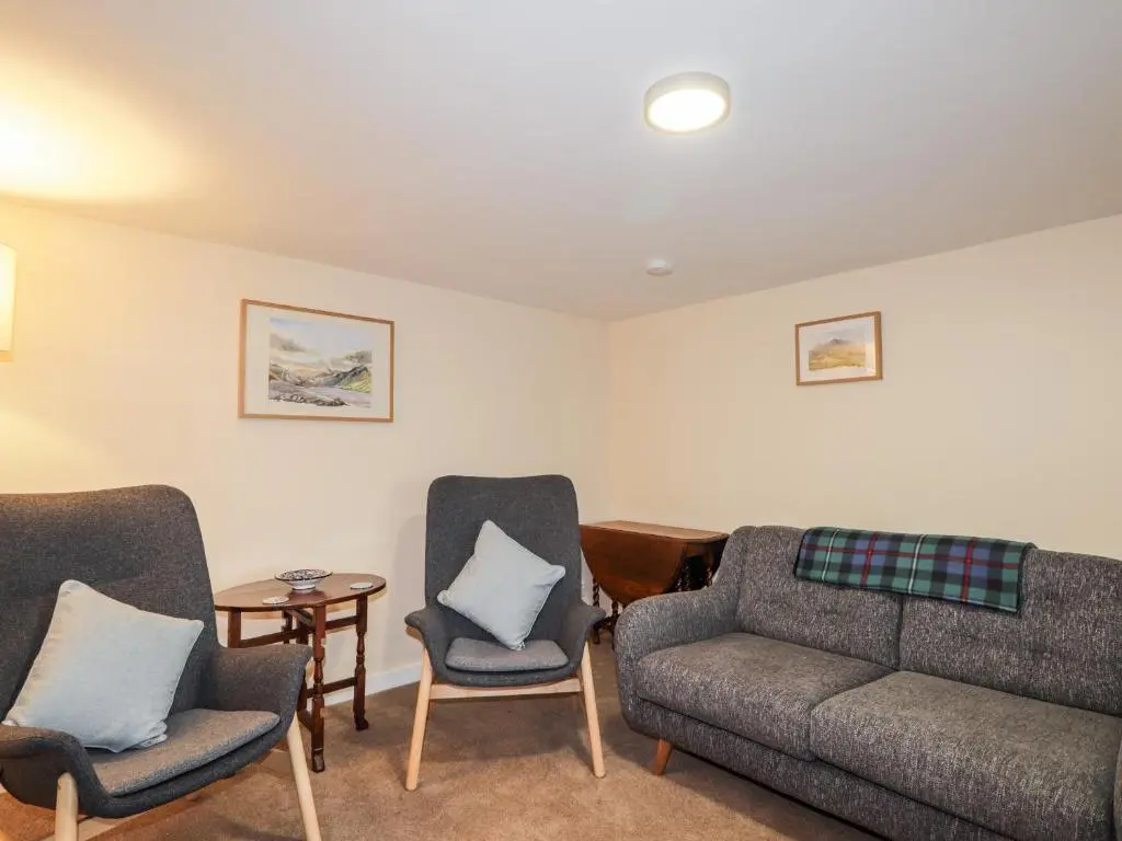 a living room with a couch and chairs and a table at Balnaird Farmhouse in Strathpeffer