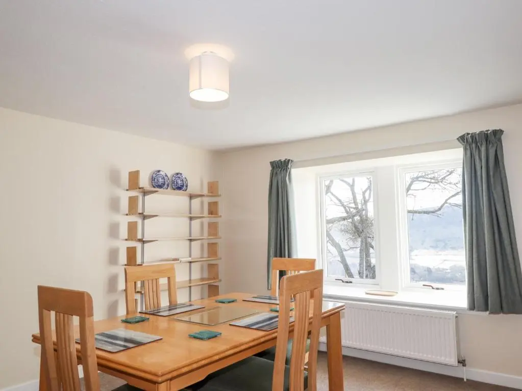 a dining room with a table and chairs and a window at Balnaird Farmhouse in Strathpeffer