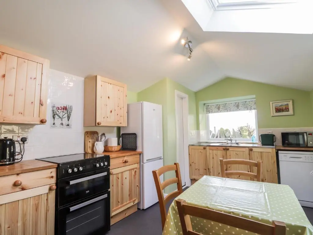 a kitchen with wooden cabinets and a table in it at Balnaird Farmhouse in Strathpeffer