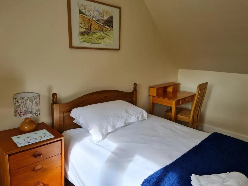 a bedroom with a bed and a night stand and a table at Balnaird Farmhouse in Strathpeffer