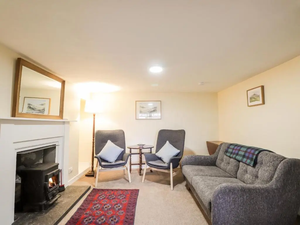 a living room with a couch and chairs and a fireplace at Balnaird Farmhouse in Strathpeffer