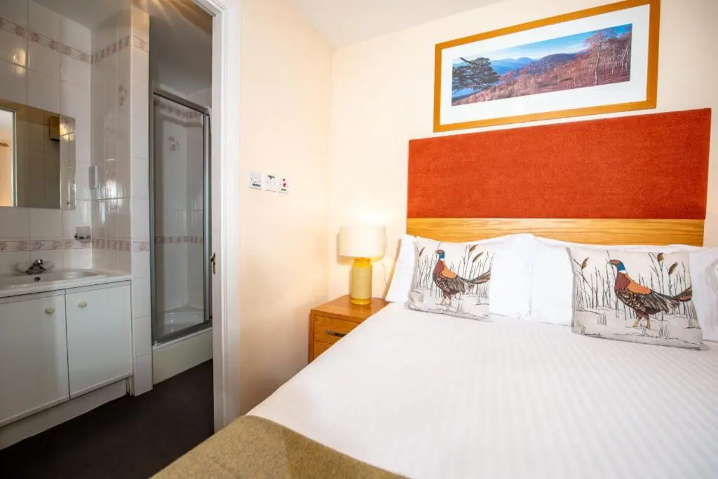 a bedroom with a large bed and a bathroom at Silverglades Holiday Homes in Aviemore
