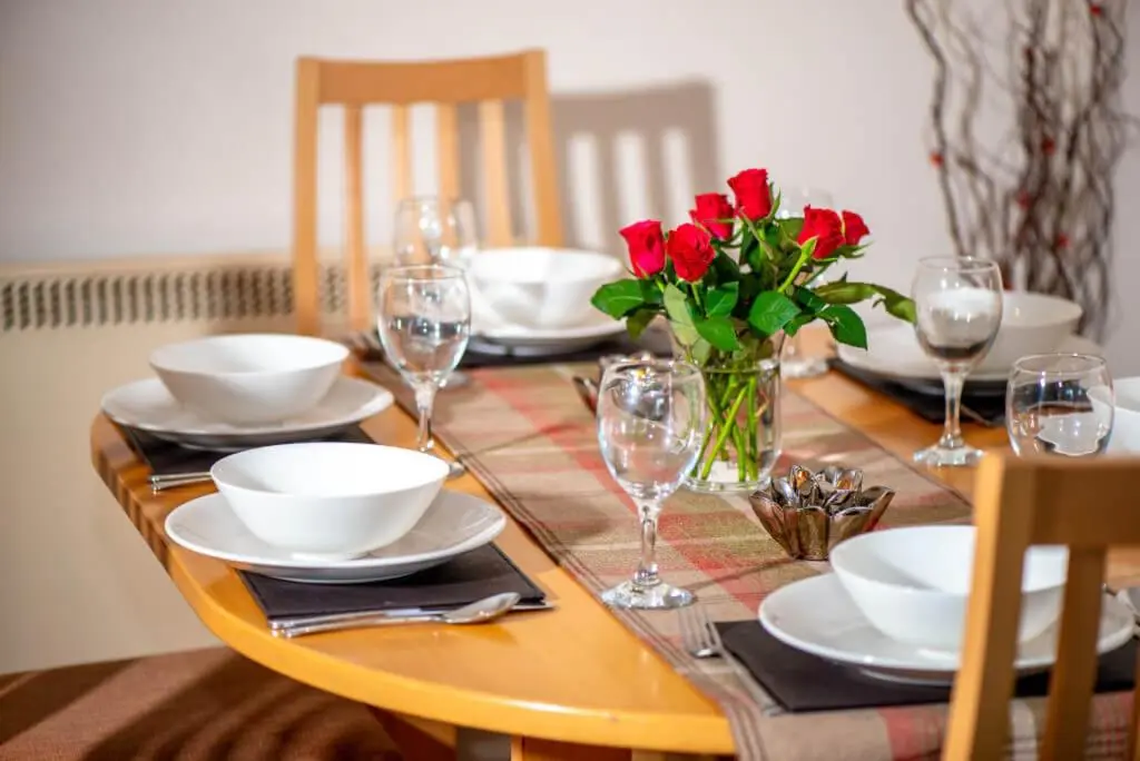 a table with plates and glasses and red roses on it at Silverglades Holiday Homes in Aviemore