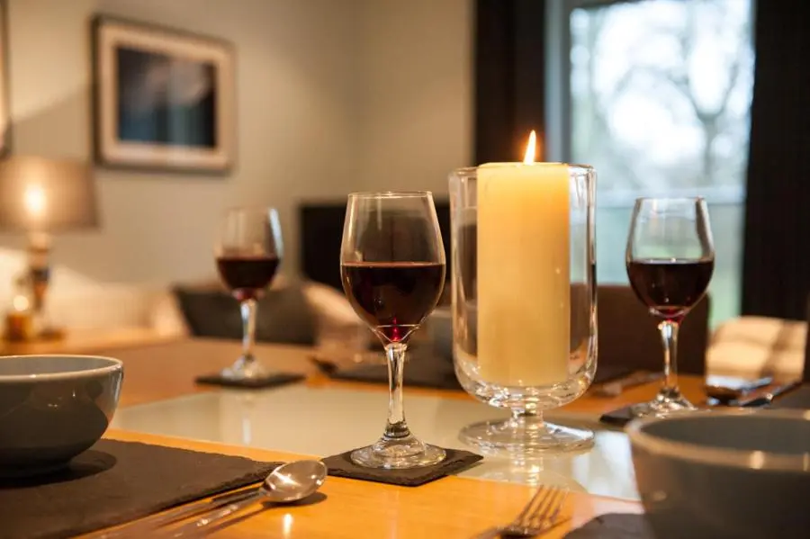 a table with wine glasses and a candle on it at Glenwood Apartment at The Highland Club in Fort Augustus