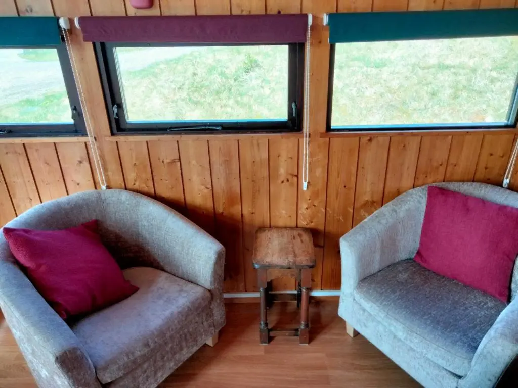 two chairs and a table in a room with windows at Highland Lodge in Kilmorack
