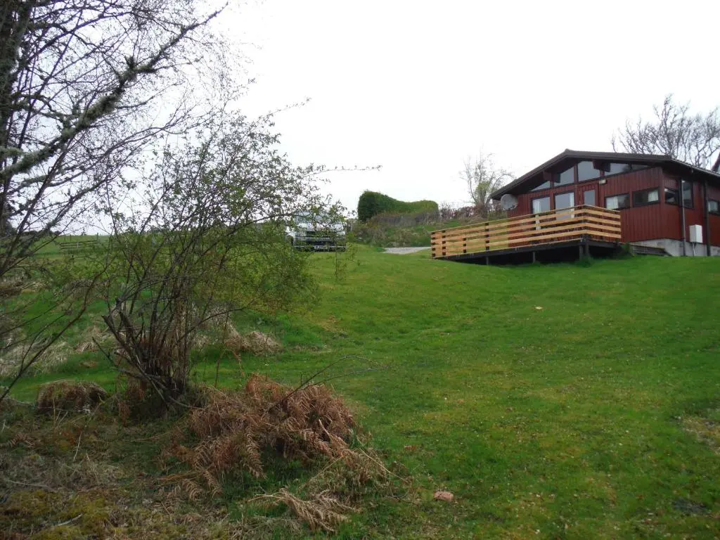 a building in a field with a grassy field at Highland Lodge in Kilmorack
