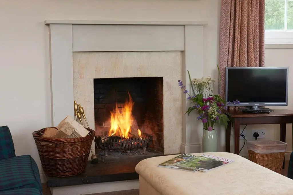 a fireplace in a living room with a fire in it at Braemoray in Evanton