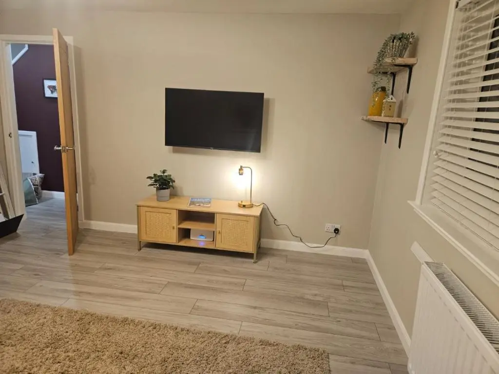 a living room with a television on a wall at No 14, 3 BED all with SMART TV's, Fully Fitted Kitchen, Ample PARKING, Ideal for TRADES, BUSINESS wanting comfort and a quality service REDUCTIONS FOR LONGER STAYS Langley Cottages and Apartments, in Wick