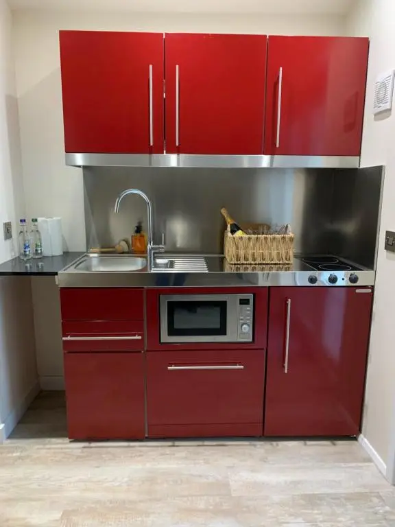 a kitchen with red cabinets and a sink at Pear Tree Cottage in Cullen