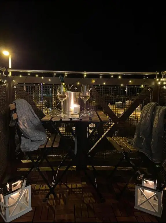a table with wine glasses on a balcony at night at Harbour and River View, Beach 50m from doorstep & free parking in Nairn