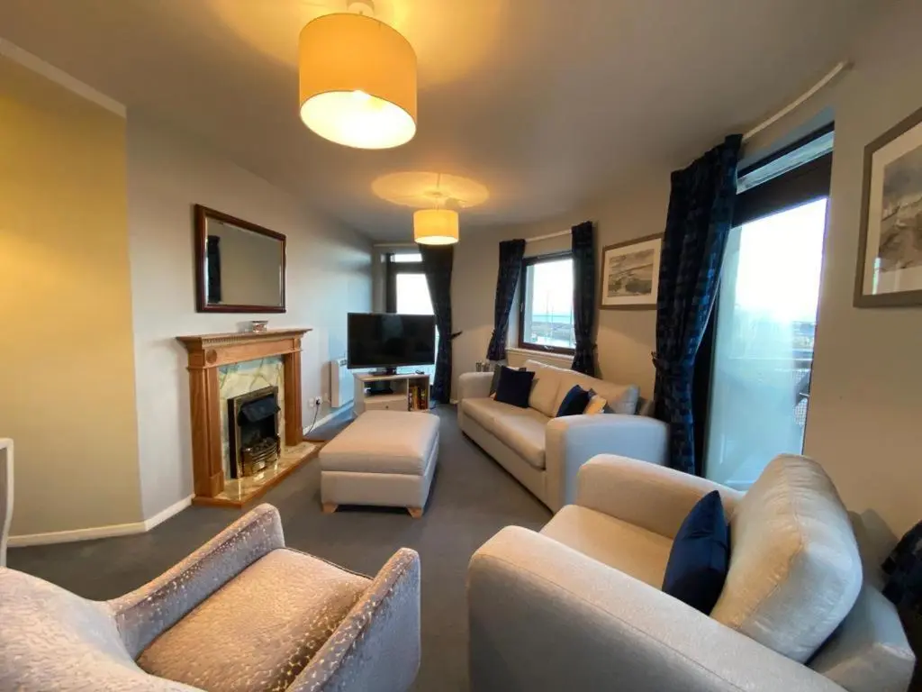 a living room with couches and a fireplace at Harbour and River View, Beach 50m from doorstep & free parking in Nairn