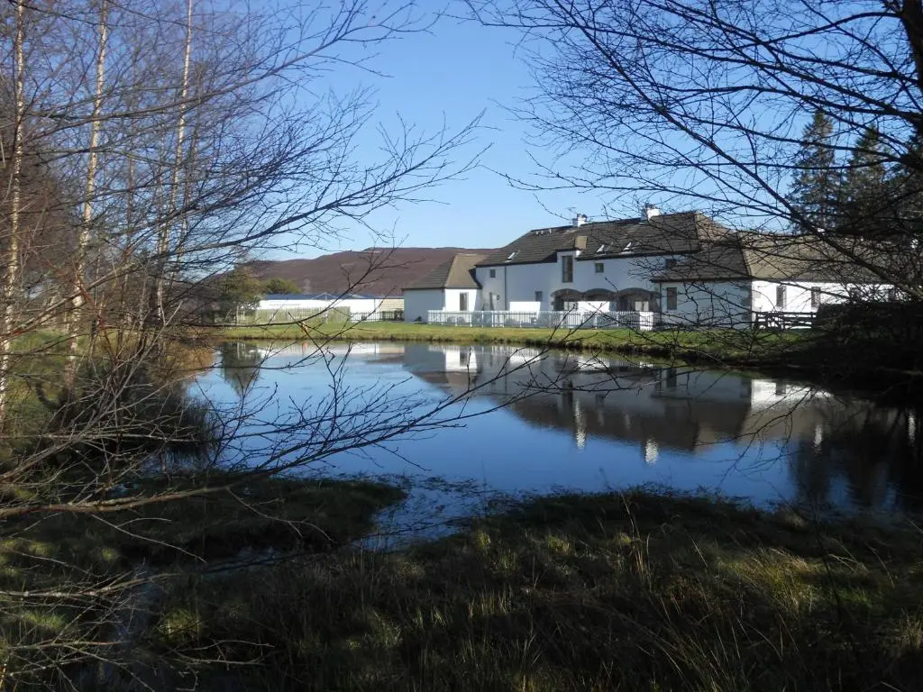 a house next to a river with a building at Highland Holiday Cottages in Newtonmore
