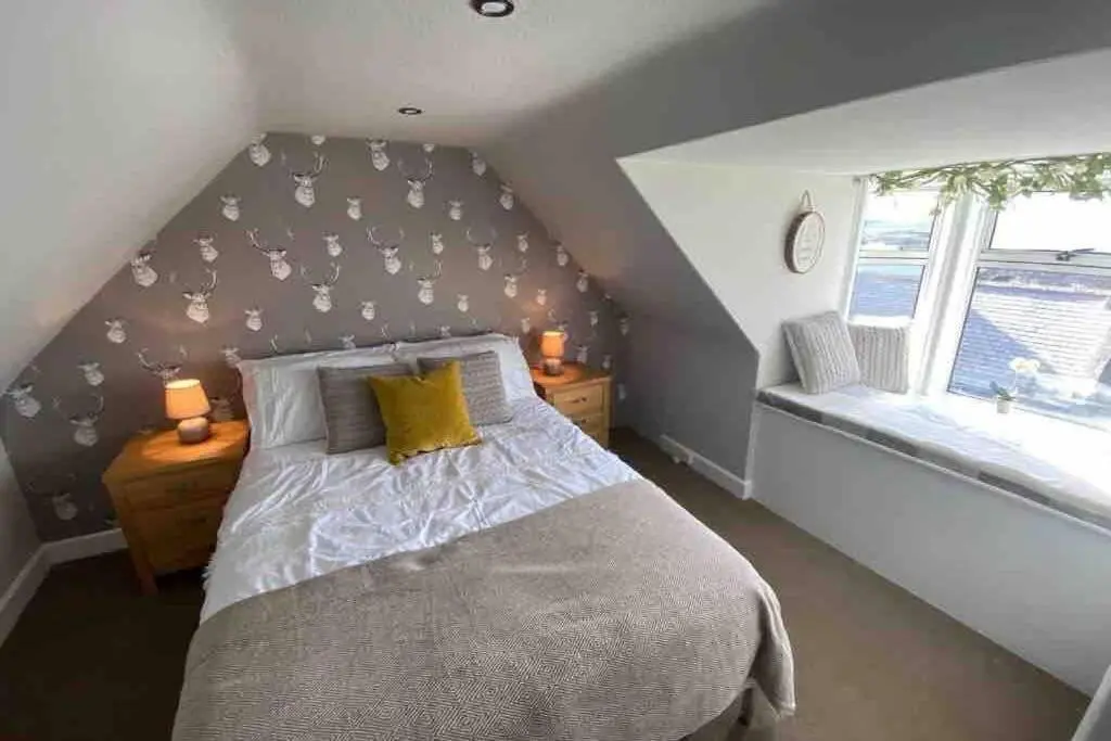 a attic bedroom with a bed and a window at Chemist's House in Cullen