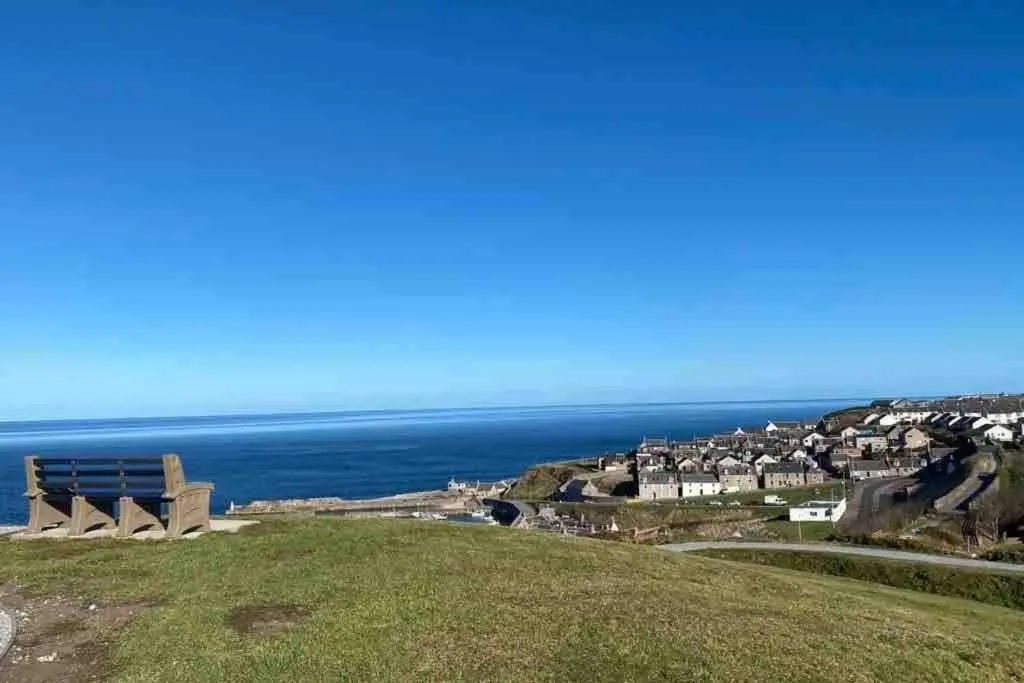 a bench on top of a hill overlooking the ocean at Chemist's House in Cullen