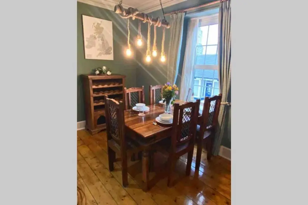 a dining room with a wooden table and chairs at Chemist's House in Cullen