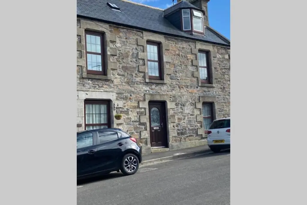 a stone house with two cars parked in front of it at Chemist's House in Cullen