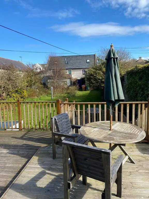 a wooden table with an umbrella and two chairs at Chemist's House in Cullen