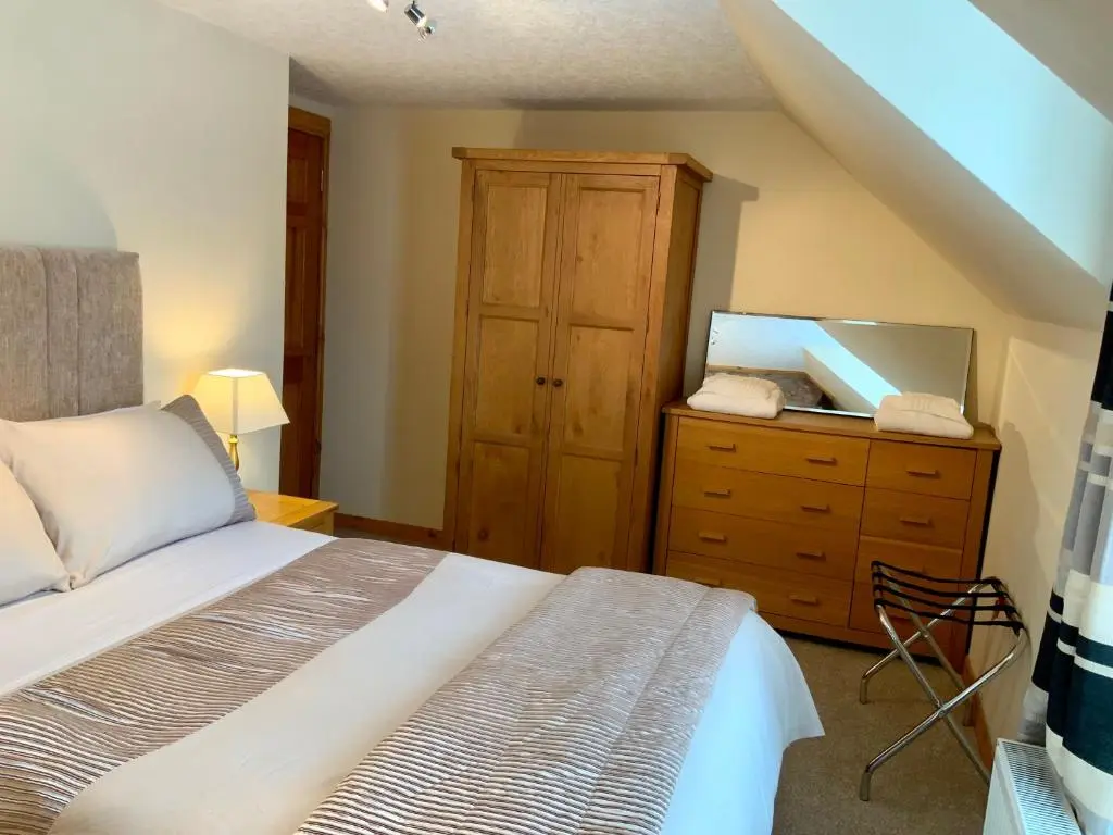 a bedroom with a bed and a wooden dresser at No 10 The Cottage in Inverness