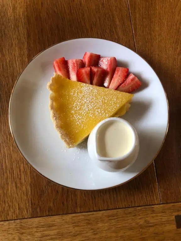 a white plate with a slice of fruit and sauce at Foresters Lodge bed and breakfast, near loch ness in Inverfarigaig