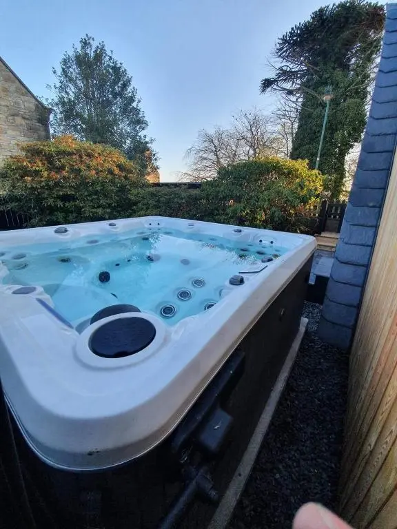 a jacuzzi tub in the backyard of a house at Little Woodbine in Tain