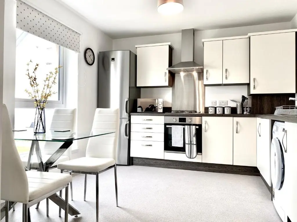 a kitchen with a glass table and white cabinets at Serviced Accommodation Moray Cawdor Avenue, Elgin in Elgin