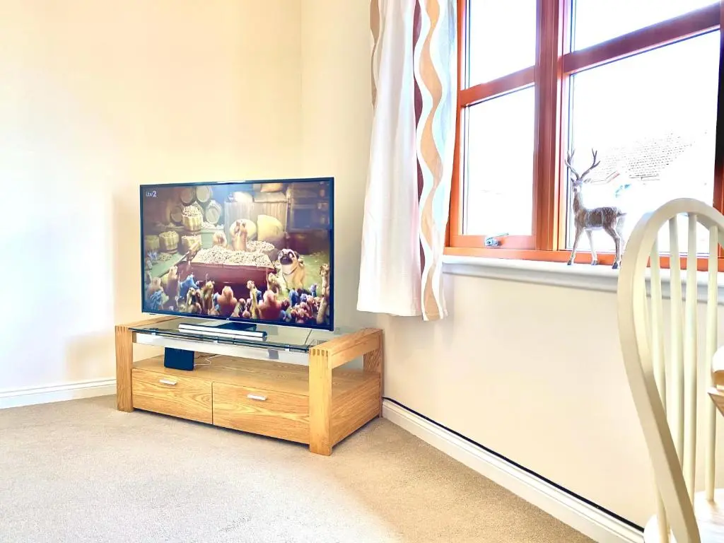 a living room with a flat screen tv on a wooden stand at 100 Thornhill Drive, Elgin in Elgin