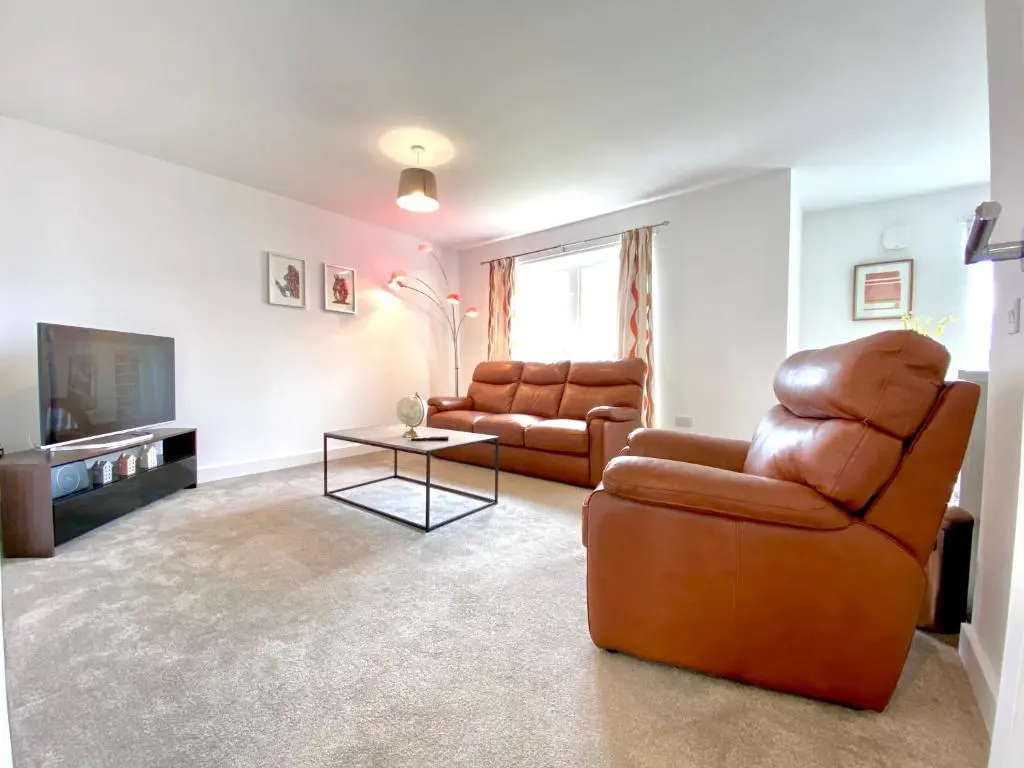 a living room with two leather chairs and a television at 100 Thornhill Drive, Elgin in Elgin