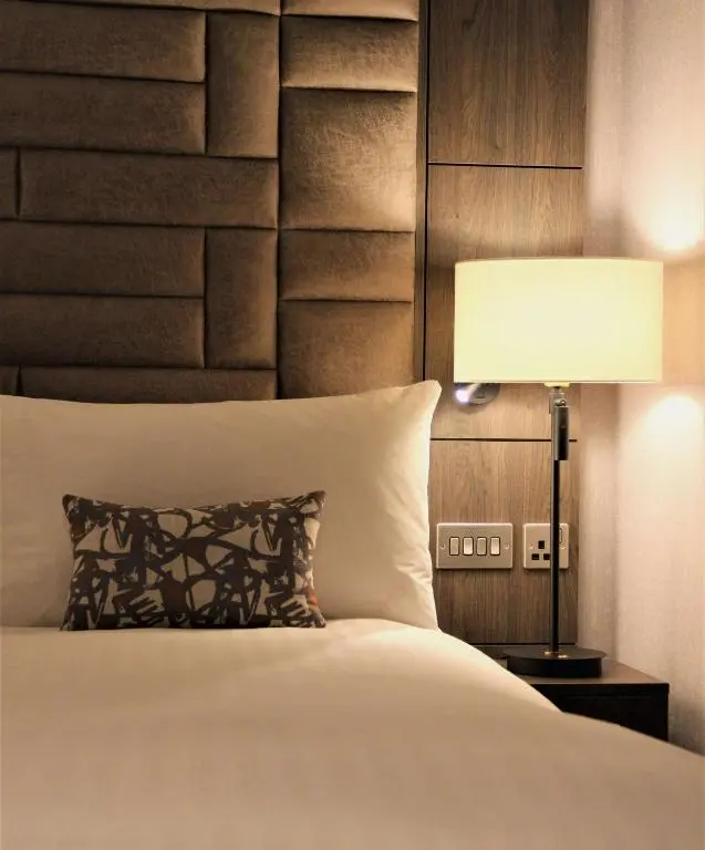 a bedroom with a bed with a lamp and a headboard at River Ness Hotel, a member of Radisson Individuals in Inverness