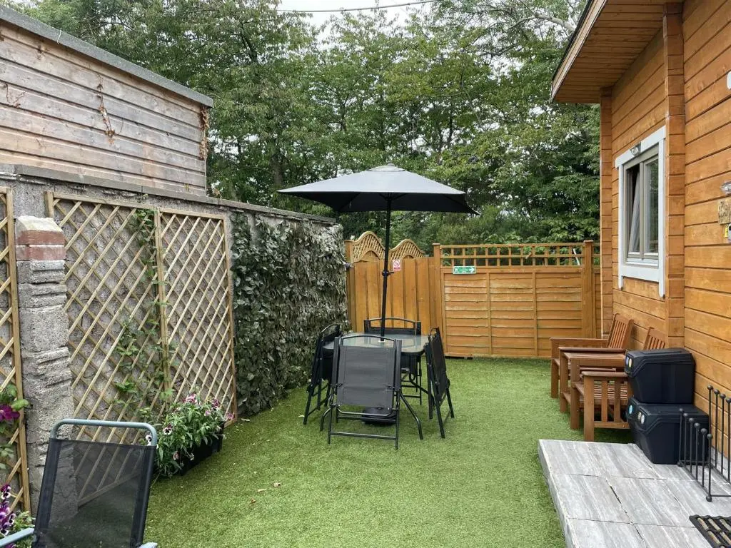 a patio with an umbrella and a table and chairs at Immaculate Cabin 5 mins to Inverness Dog friendly in Inverness