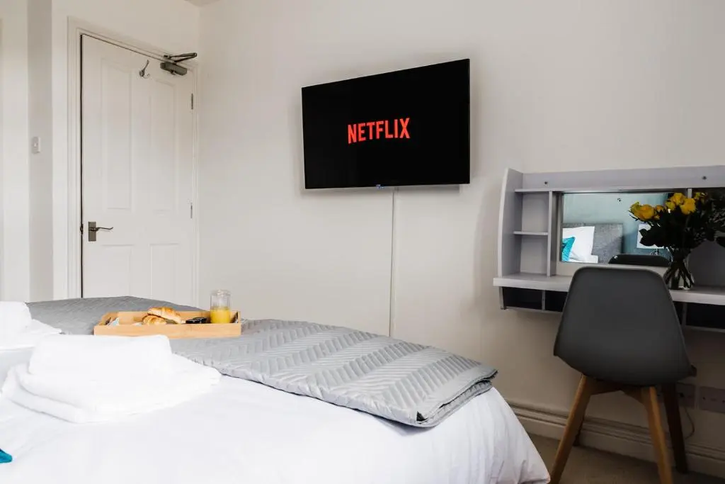 a bed with a chair and a tv on the wall at Seaforth House Apartment in Elgin