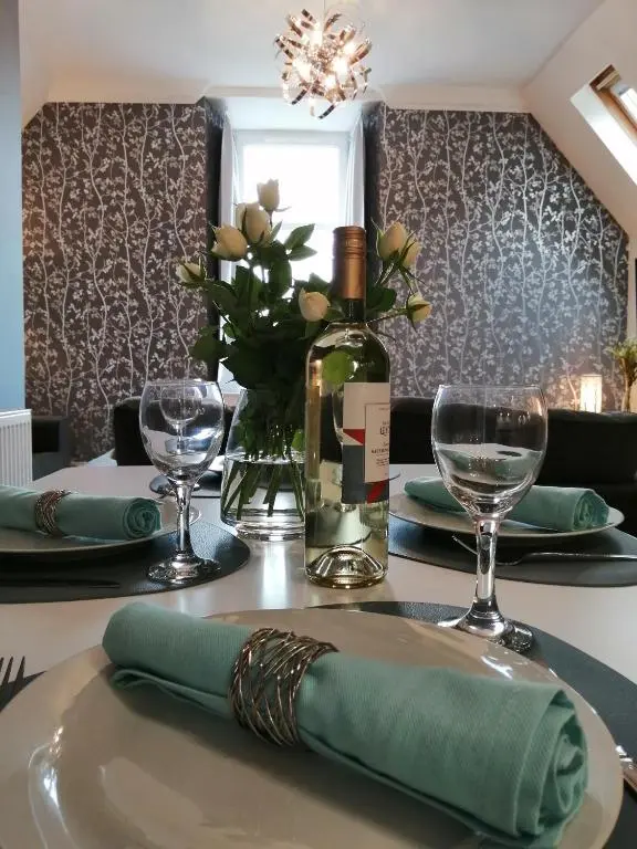 a table with a green napkin and a bottle of wine at Seaforth House Apartment in Elgin