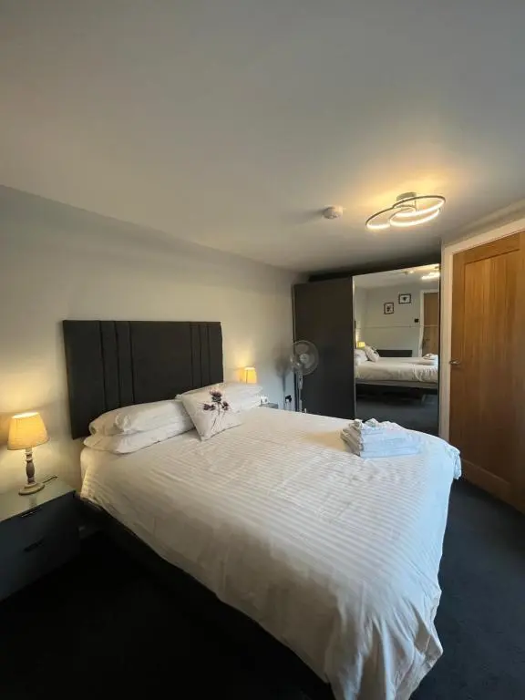 a bedroom with a large white bed and a mirror at Shore Street Apartments in Inverness