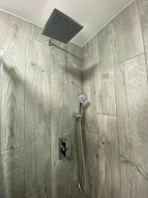 a shower with a shower head in a bathroom at Shore Street Apartments in Inverness