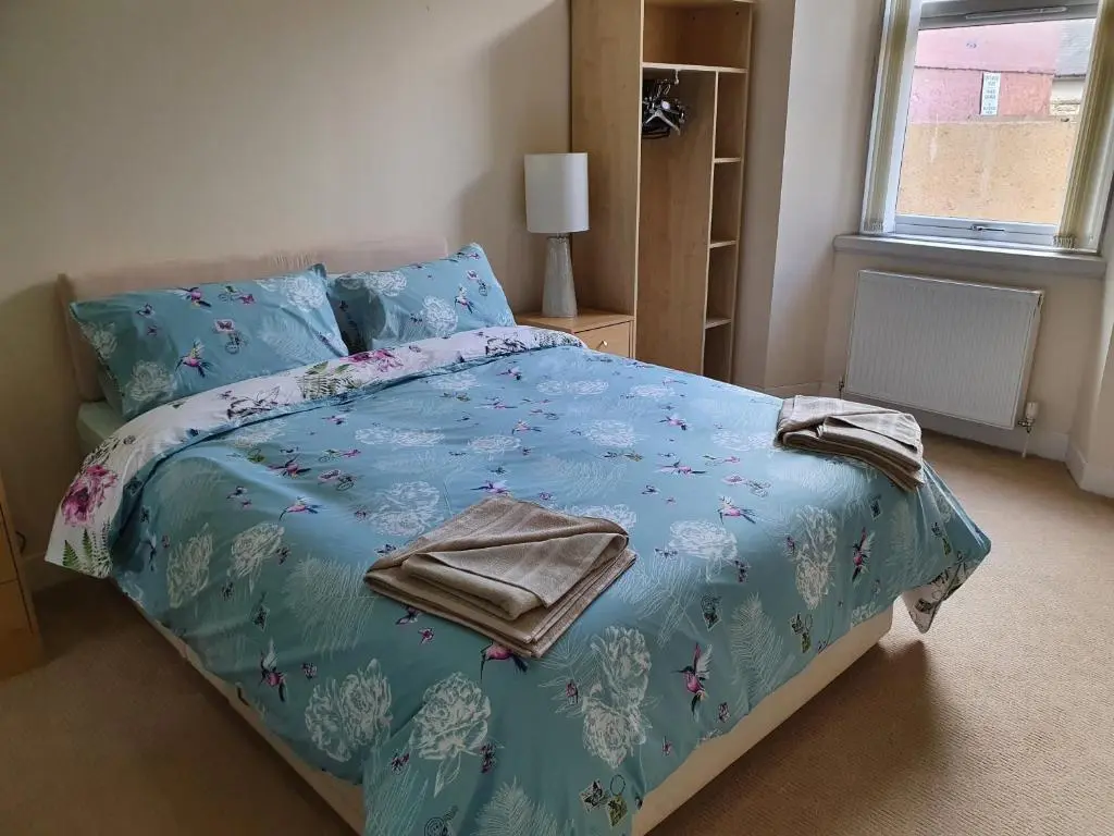 a bedroom with a bed with a blue comforter at Flat 1 Castlebank house Flats in Dingwall