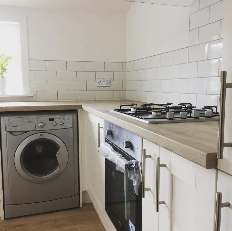 a kitchen with a stove and a washing machine at Islas Cottage, a home in the Heart of Speyside in Dufftown