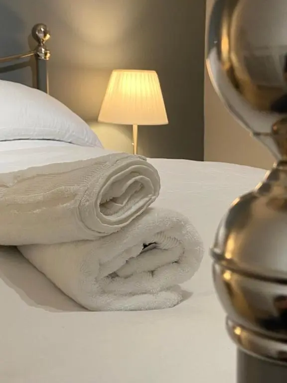 a white towel sitting on a bed next to a lamp at Islas Cottage, a home in the Heart of Speyside in Dufftown