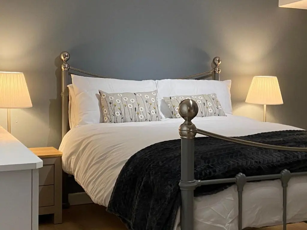 a bedroom with a bed with white sheets and two lamps at Islas Cottage, a home in the Heart of Speyside in Dufftown