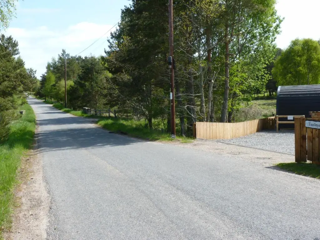 an empty road next to a fence and trees at Tanleys B&B in Grantown on Spey