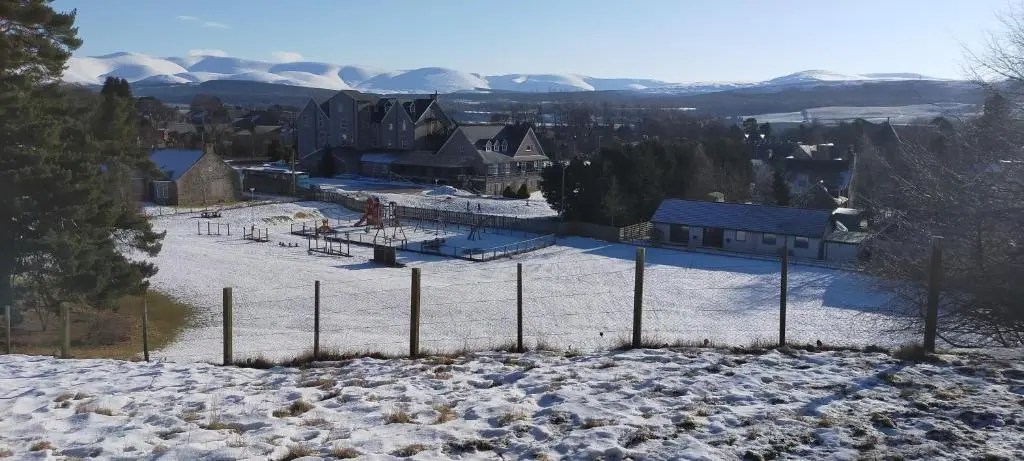 a town in the snow with a fence at Ardvonie House in Kingussie