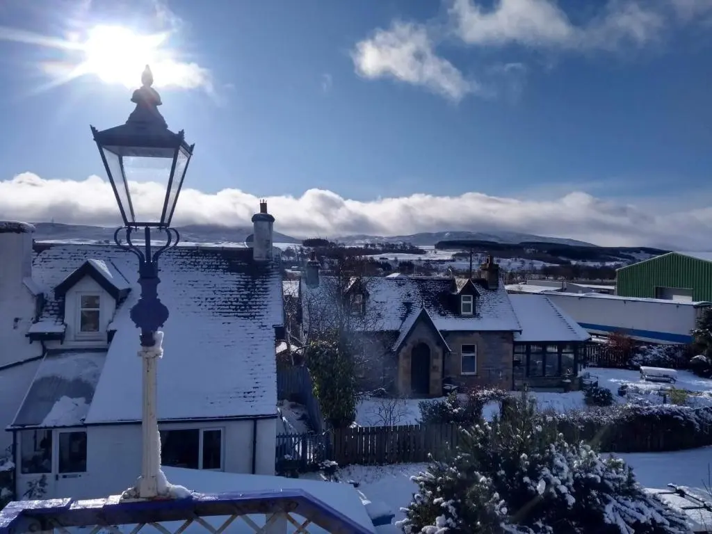 a street light with the sun shining in the snow at Ardvonie House in Kingussie