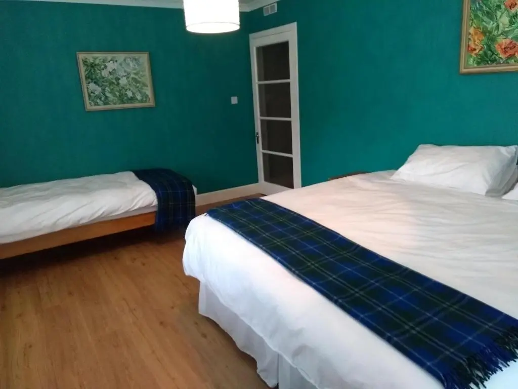 a bedroom with two beds and a green wall at Ardvonie House in Kingussie