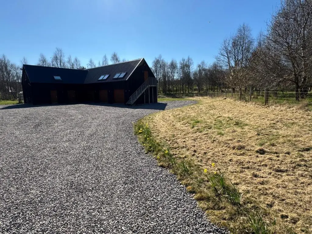 a building with a black roof on a gravel road at Willowbarn Rafford Self Catering in Forres