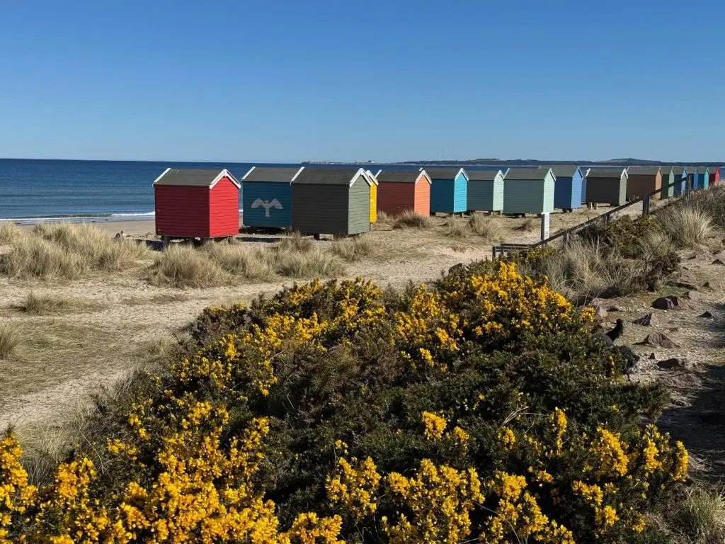 a row of colorful beach huts on the beach at Willowbarn Rafford Self Catering in Forres