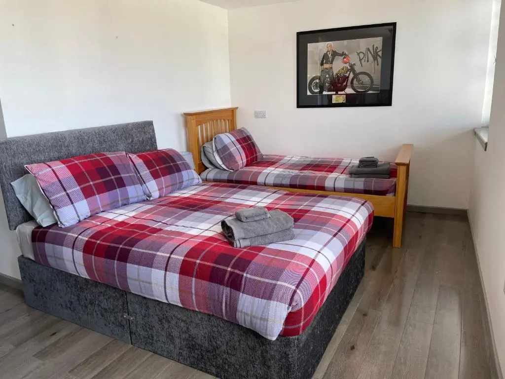 a bedroom with two beds and a plaid blanket at Rooms in Inverness in Inverness