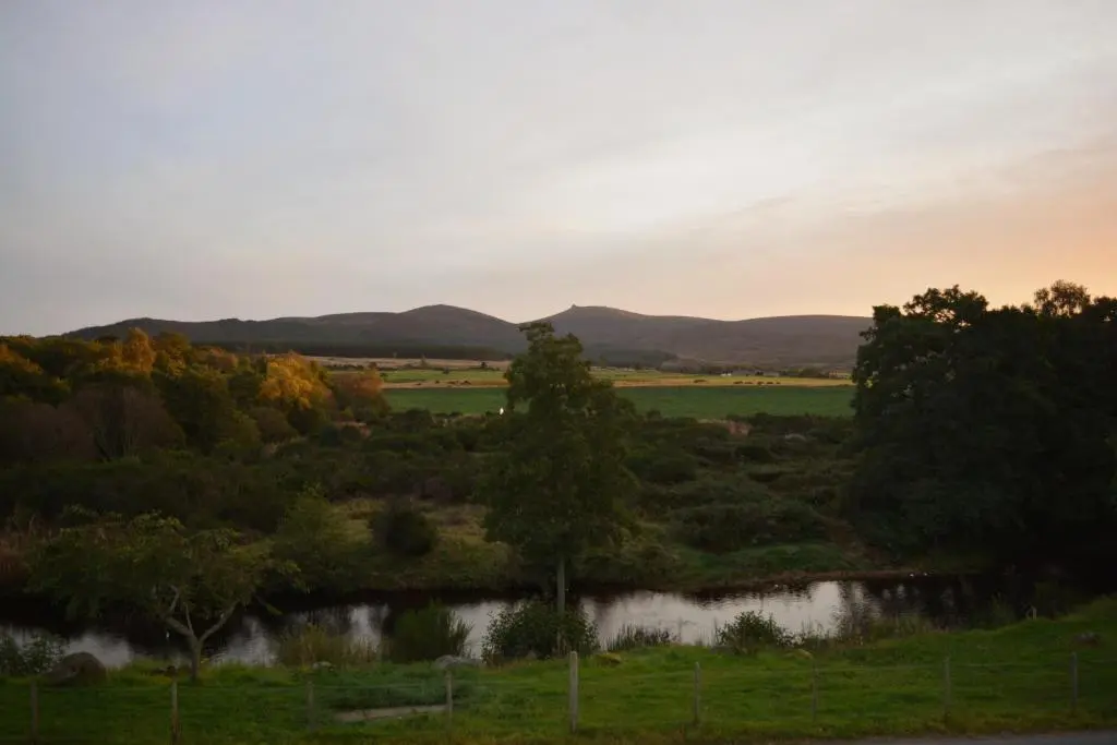 a view of a field with trees and a river at Feughside in Strachan
