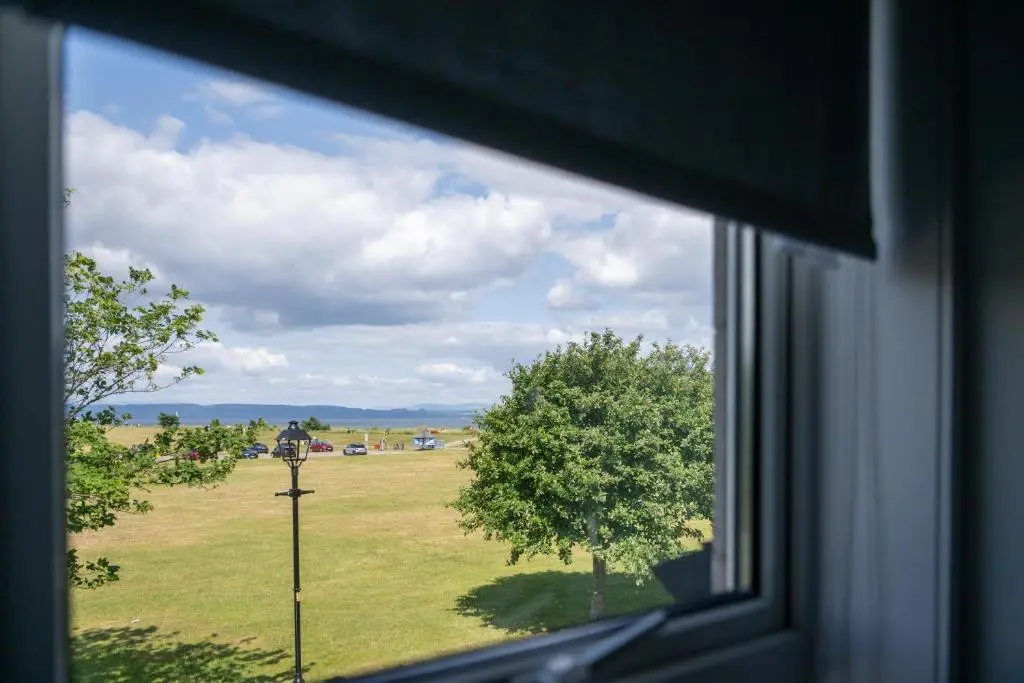 a view from a window of a field with a tree at Seaview House - A Traditional Home by the Beach in Nairn