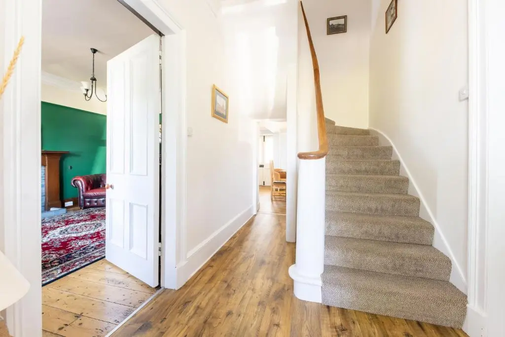 a staircase in a home with white walls and wooden floors at Seaview House - A Traditional Home by the Beach in Nairn