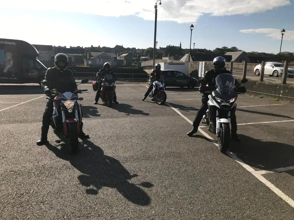 a group of people riding motorcycles in a parking lot at Harbour bridge, Camps bar in Wick